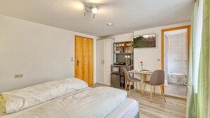 A bedroom with a bed, a desk with a computer, a chair, and a small kitchenette. - Lovely apartment in Bischofsheim with WiFi (Bischofsheim)