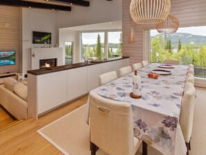 A modern kitchen with a large island, a dining area with a floral tablecloth, and a fireplace.