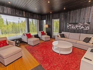 A modern living room with a red carpet, wooden walls, and a large window. - Holy lake chalet a by Interhome (Kuusamo)