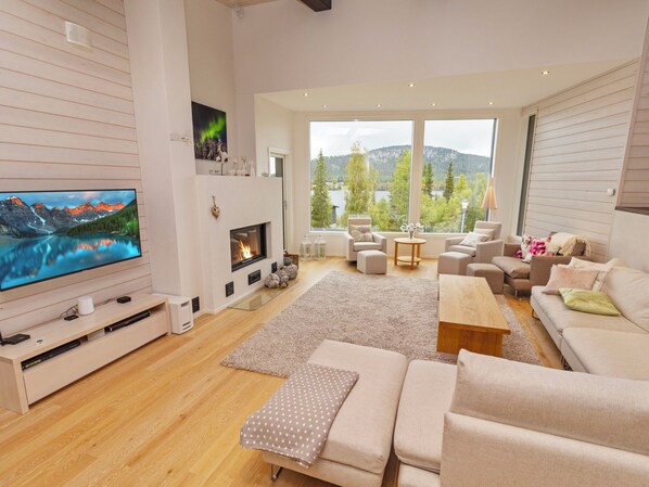 A modern living room with a fireplace, a television, and a large window offering a scenic view.