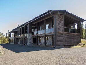 A modern two-story building with a stone facade, large windows, and a balcony. - Holy lake chalet a by Interhome (Kuusamo)