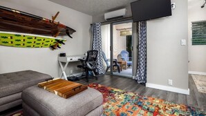 Una sala de estar moderna con un sofá gris, una mesa de centro de madera, un escritorio con una silla y un tapete colorido.