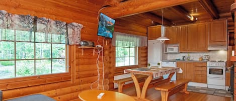 L’intérieur d’un chalet accueillant, avec une table à manger en bois, un canapé et un coin cuisine.