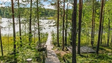 A wooden boardwalk leading to a dock over a calm lake, surrounded by dense forest.