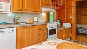 Cocina compacta con armarios de madera, microondas, hervidor, tostadora y lavavajillas.