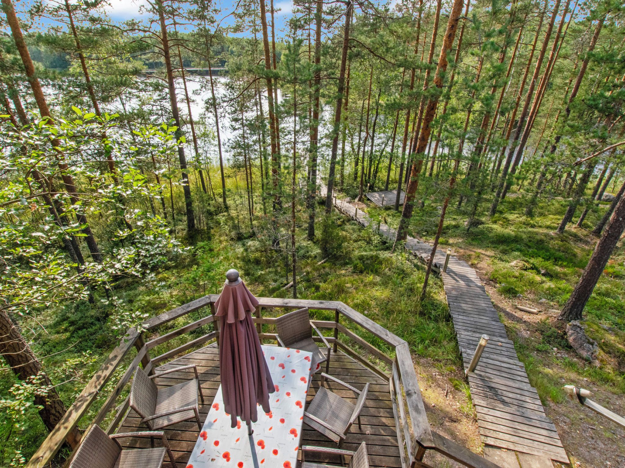 Una terraza de madera con una mesa y sillas, con vistas a un bosque y un lago.