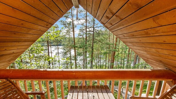 Una terraza de madera con bancos, con vista a un área boscosa.