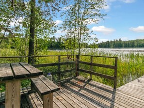 En træterrasse med picnicborde med udsigt over en sø.