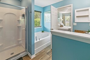 A bathroom with a glass shower enclosure, a freestanding bathtub, and a vanity with a mirror. - Charming 3-bedroom house in Jacksonville (Jacksonville)