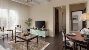 Ein Wohnzimmer mit Fernseher, Esstisch, Stühlen und einem dekorativen Schrank.