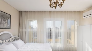 Ein Schlafzimmer mit Bett, Vorhängen, einer Kristallleuchter und Blick auf die Stadt.