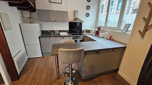 A compact kitchen with a central island, a microwave, a stove, and a refrigerator.