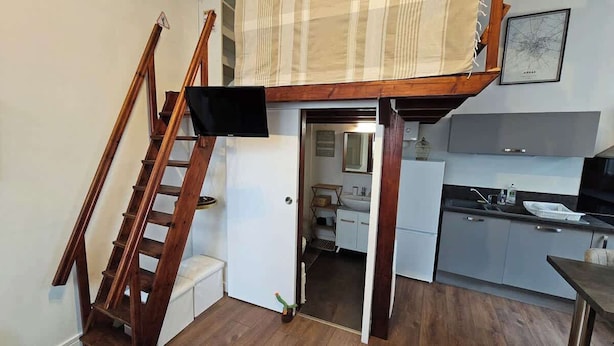 A compact kitchen with a wooden ladder, a small dining table, and a kitchenette area.