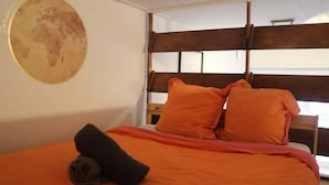 A bed with orange bedding, a wooden headboard, and a world map on the wall.
