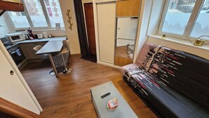 A compact living space with a kitchenette, a sofa, and a dining area.