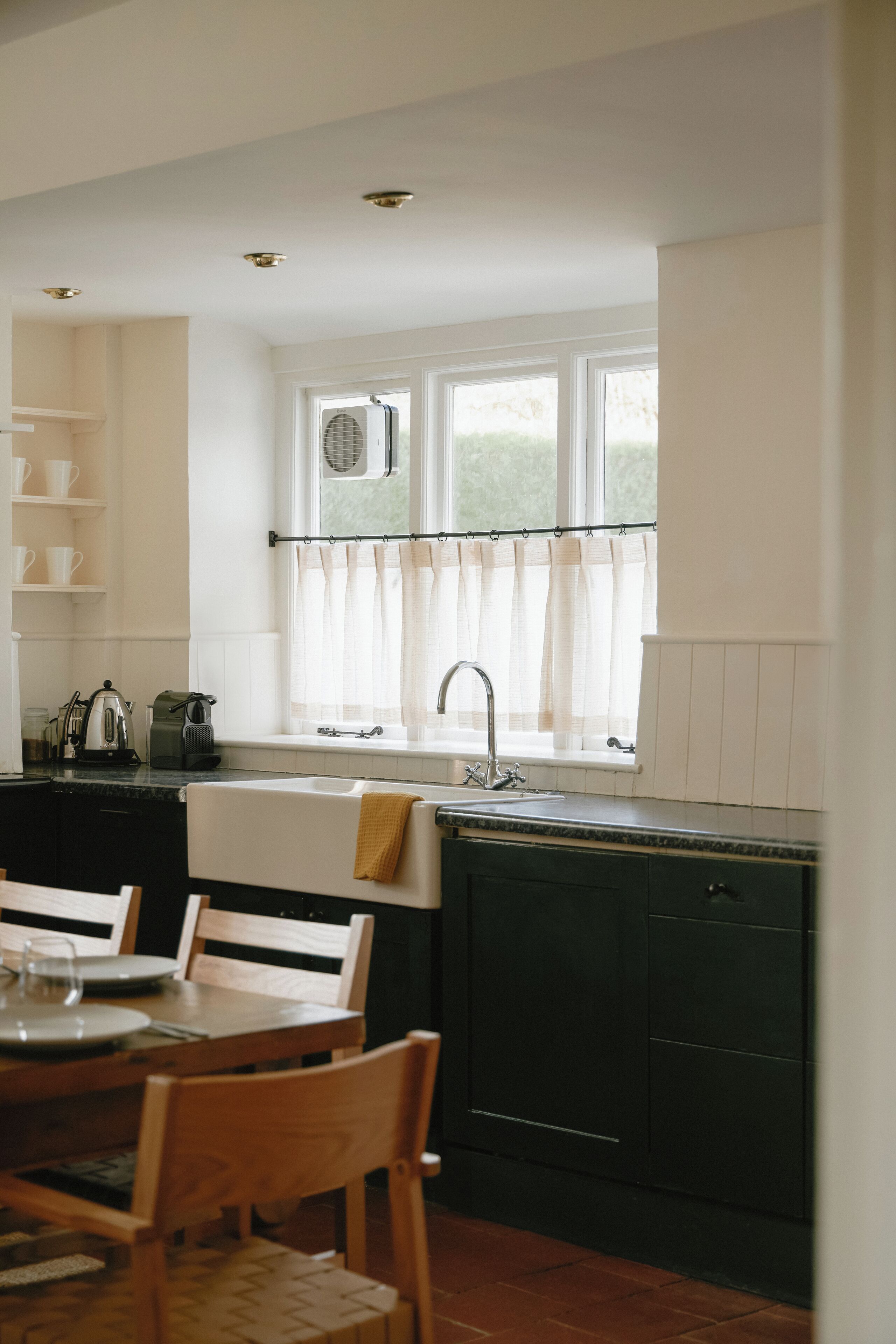 A kitchen with a window, sink, and a dining area with chairs and a table.