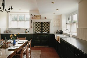 Une cuisine avec un dosseret à carreaux, une cuisinière et un coin repas avec une table dressée pour quatre personnes.