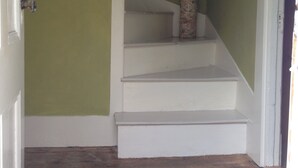 Eine Treppe mit weißen Stufen und einer grünen Wand, ein Tomatenbild und ein gemustertes Teppich.