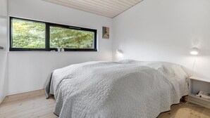 A bedroom with a large bed, a window with a view of trees, and a bedside table with a lamp. - Cozy home in Hornbæk with WiFi (Hornbæk)