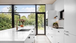 A modern kitchen with a large island, a sink, and a view of the outdoors. - Cozy home in Hornbæk with WiFi (Hornbæk)