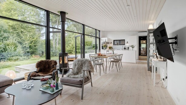 A modern interior with a large window, a fireplace, a dining area, and a TV mounted on the wall. - Cozy home in Hornbæk with WiFi (Hornbæk)