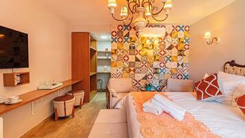 A hotel room with a bed, a TV, a wooden desk, and a colorful tiled wall.