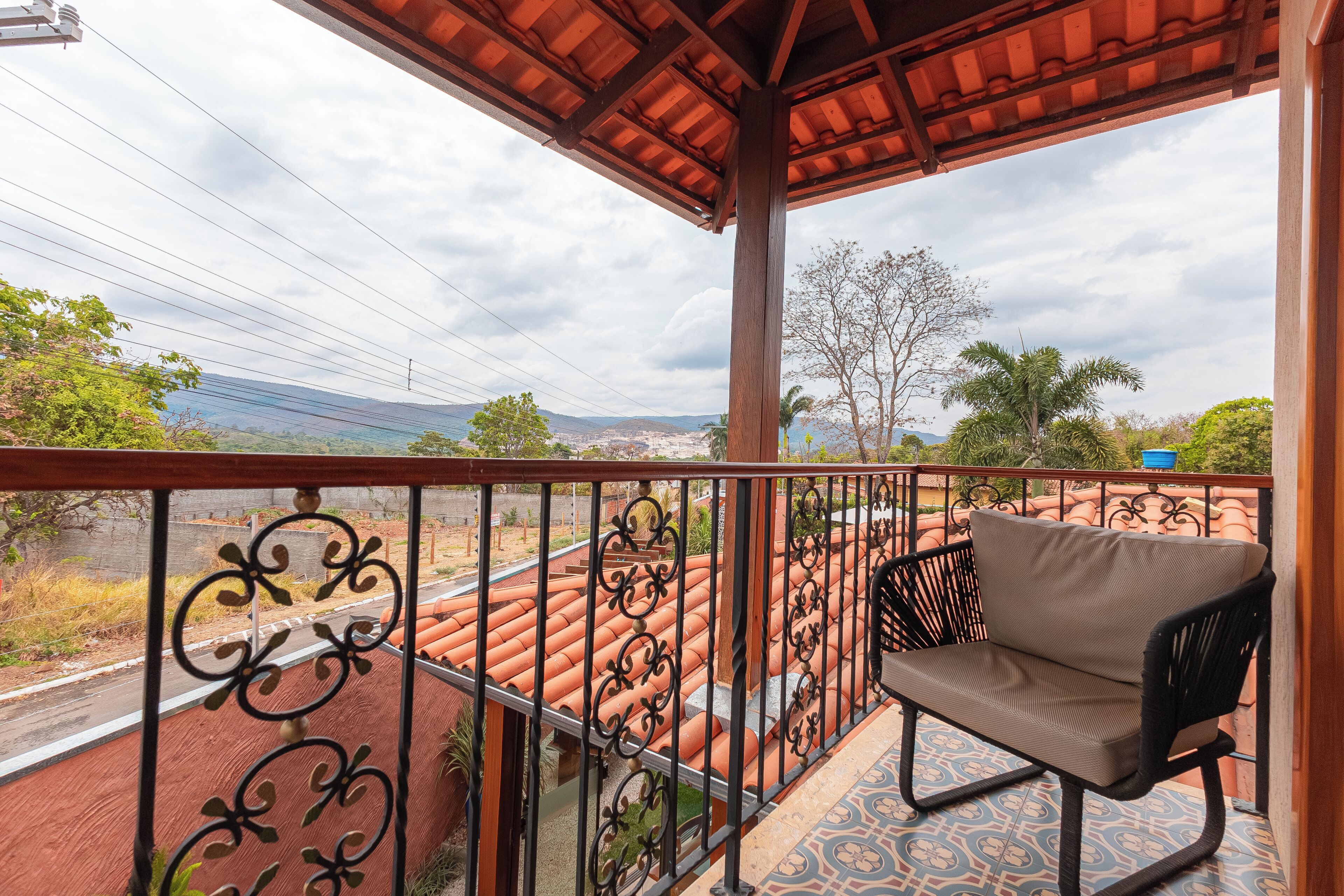 Un balcon avec une chaise, un sol carrelé et une vue sur le paysage.