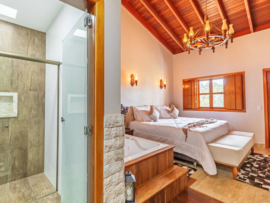 Un dormitorio con cama, ventana, candelabro y techo de madera.