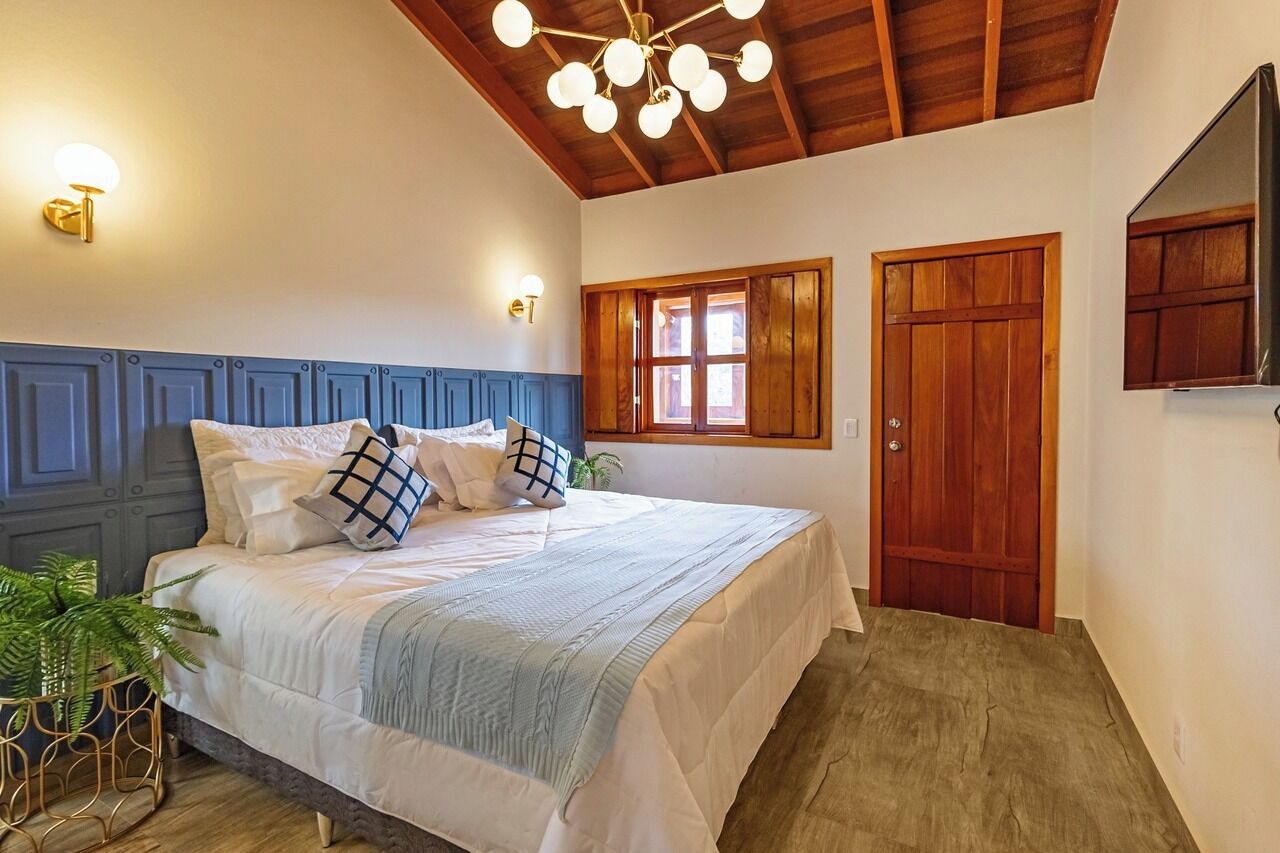 A bedroom with a bed, a wooden door, a window, and a ceiling light fixture.