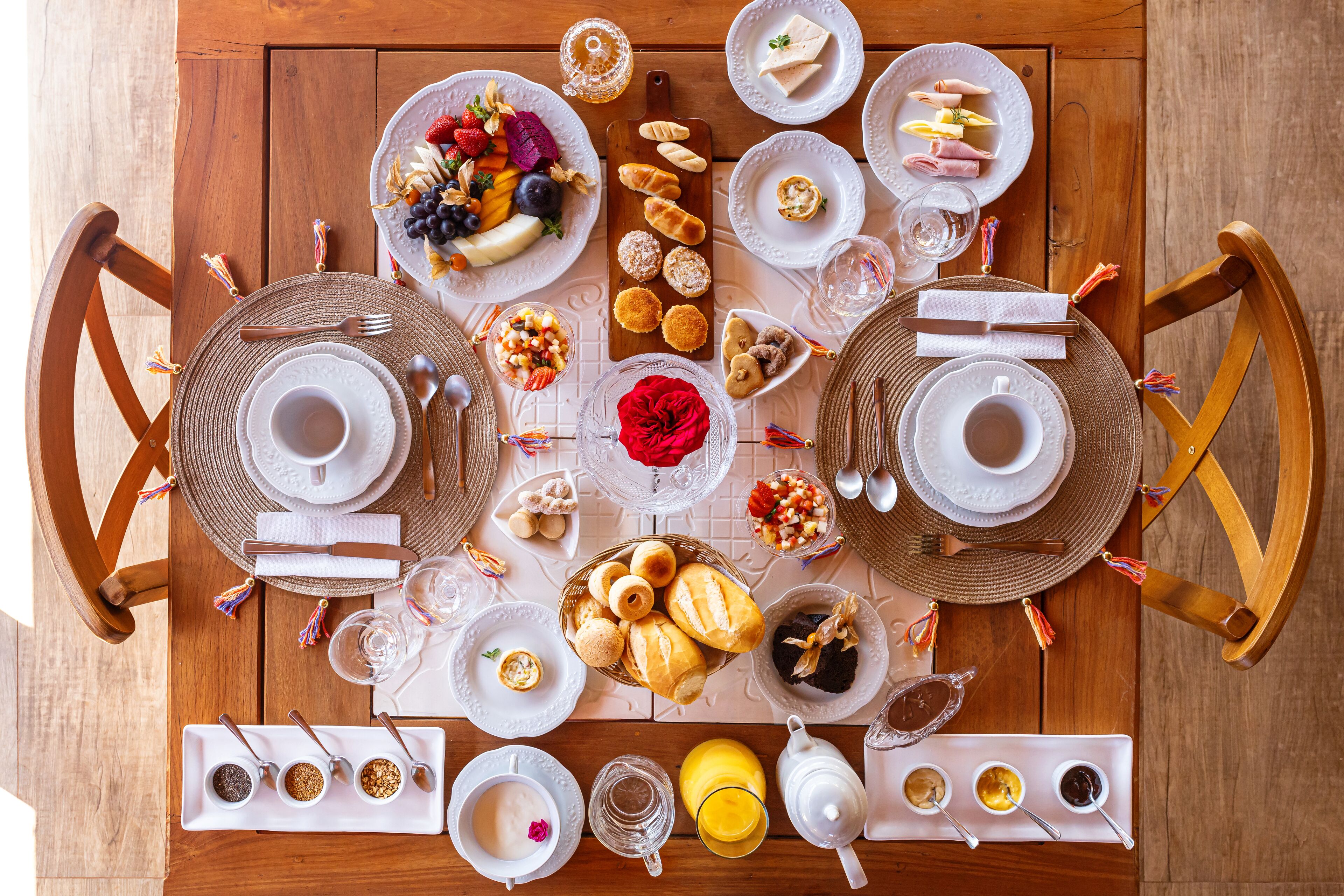 Une table de salle à manger en bois, mise pour un repas, avec des assiettes, des couverts et différents plats.