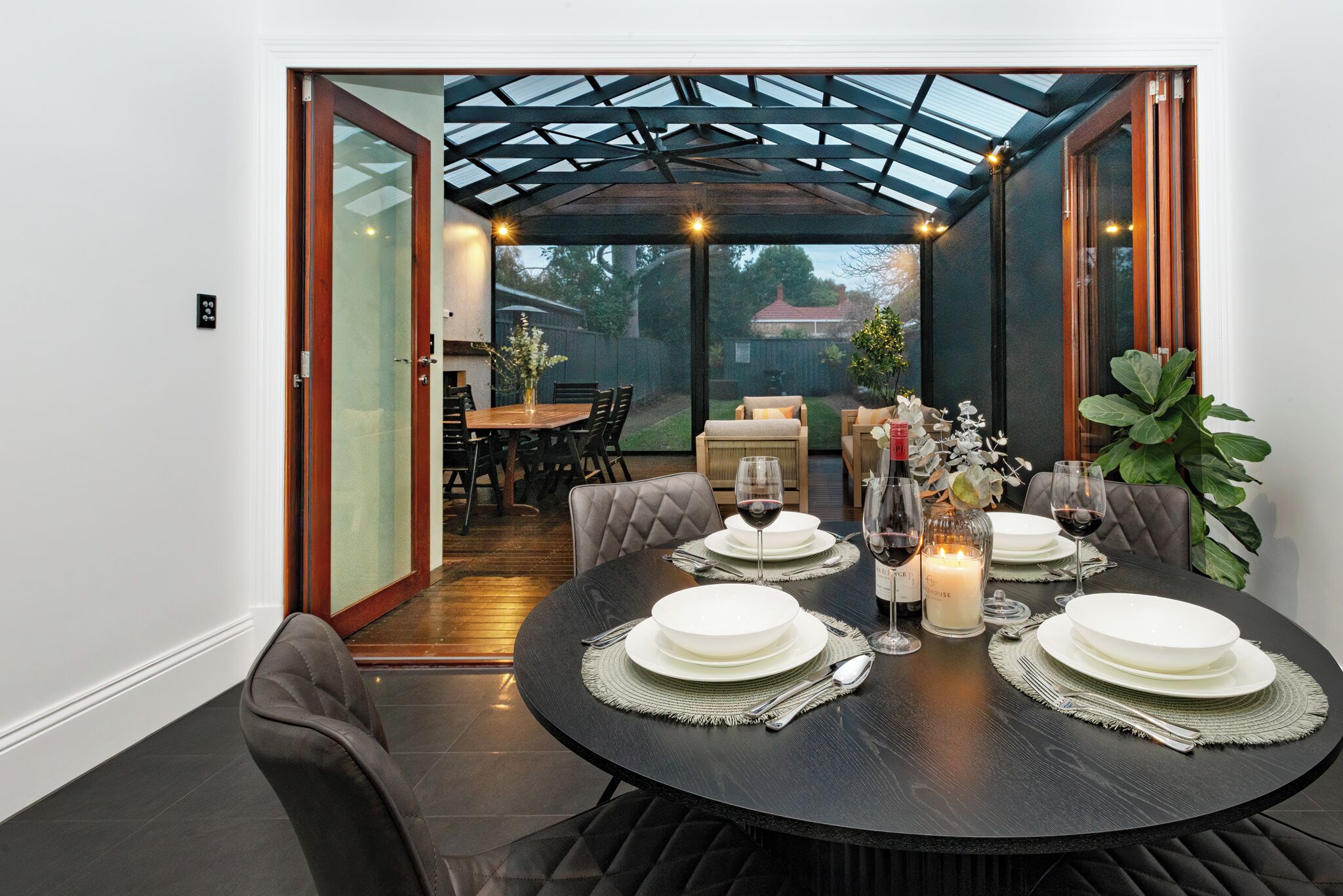 A dining area with a round table set for four, surrounded by cushioned chairs.