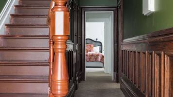 A wooden staircase leading to a bedroom with a bed and a nightstand.