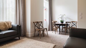 A living room with a sofa, a rug, and a dining area with chairs and a table. - Premium Living on Stuart Street (Dunedin)
