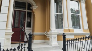 A two-story building with a yellow facade, white trim, and a black iron fence. - Premium Living on Stuart Street (Dunedin)