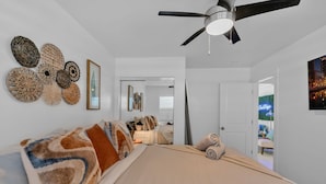 Une chambre à coucher avec un lit, un ventilateur de plafond et des éléments de décoration murale.