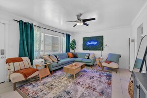 A modern living room with a sectional sofa, a coffee table, a side table, a chair, and a ceiling fan.