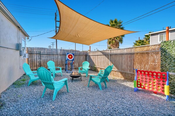 A backyard with a fire pit, outdoor chairs, and a badminton net.