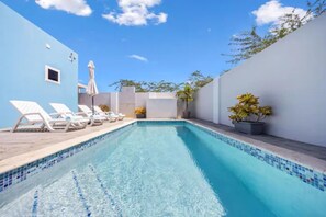Una piscina con acqua cristallina, circondata da pareti bianche e un cielo azzurro.