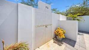 Un espacio exterior moderno con una pared blanca, una planta en maceta y un suelo de baldosas.