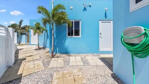 Un edificio azul con una puerta blanca, una ventana y una manguera verde a la derecha.