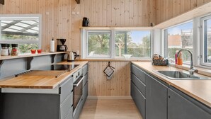 A modern kitchen with wooden walls, a large window, and a built-in oven.