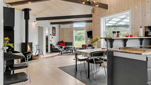 A modern kitchen with a large window, a built-in stove, and a dining area with chairs and a table.