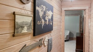 Ein Holzinterieur mit einer Weltkarte als Bild, einem gerahmten Landschaftsbild und einem Wandbehang aus Makramee.