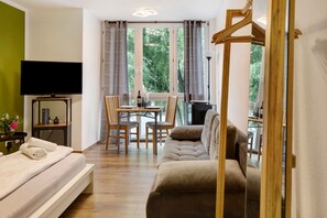 A room with a bed, a sofa, a dining table with chairs, a TV, and a window with curtains. - Studio at Freiburg Train Station with Wi-Fi (Freiburg im Breisgau)