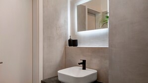 Ein Badezimmer mit einem weißen Waschbecken, einem schwarzen Wasserhahn und einem Spiegel darüber.