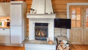 A cozy cabin interior with a fireplace, a television mounted on the wall, and a wooden door. - 2 bedroom lovely home in Oppdal (Oppdal)