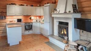 A cozy cabin-style kitchen with wooden cabinets, a built-in oven, a microwave, and a fireplace. - 2 bedroom lovely home in Oppdal (Oppdal)