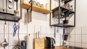 A kitchen with a wooden countertop, a coffee maker, a knife block, and a hanging set of blue scissors.