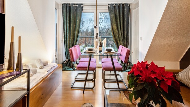 A modern living room with a dining area, a large window with curtains, a sofa, a coffee table, and a potted plant.