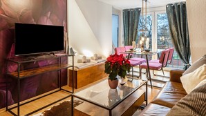 A modern living room with a glass coffee table, leather sofa, and a flat-screen TV on a stand.